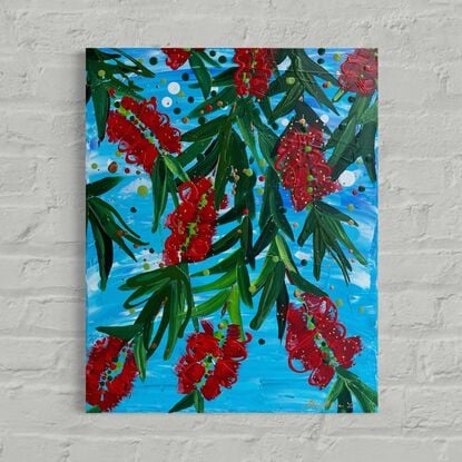 Close up of 9 bright red bottlebrush flowers hanging from a tree with a bright blue sky background. 