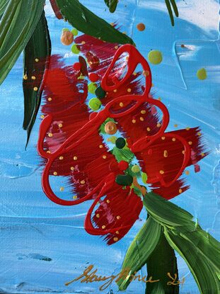 Close up of 9 bright red bottlebrush flowers hanging from a tree with a bright blue sky background. 