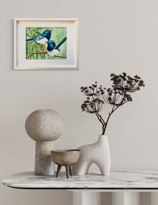 Two tiny Australian Blue Wren's sitting on a branch with a few Eucalyptus leaves