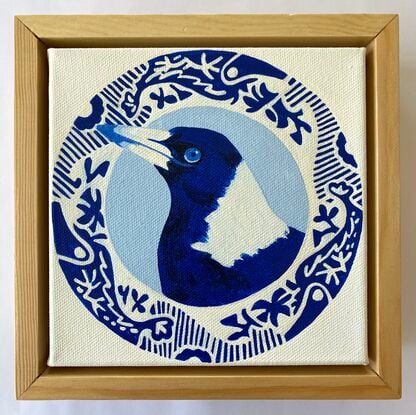 Magpie bird surrounded by a round patterned border painted in blue and white 