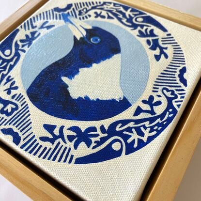 Magpie bird surrounded by a round patterned border painted in blue and white 