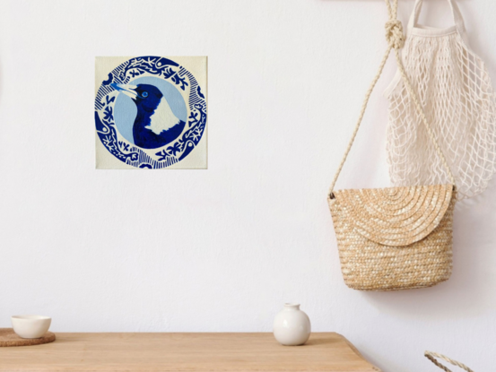 Magpie bird surrounded by a round patterned border painted in blue and white 