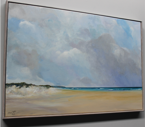 Sand dunes leading into a wide beach scene with calm sea and cloudy sky