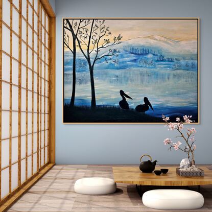 This artwork features a serene, wintry landscape, inspired by the artist's travels through New Zealand. The mountain range in the background, softly covered in snow, reflects the fresh, crisp atmosphere of icy mornings in the region. The hues of blue dominate the scene, evoking the cold, tranquil beauty of the landscape. The sky transitions from soft yellow to cool blues, suggesting the early hours of sunrise or sunset, when the sun gently lights the frosted environment.

In the foreground, silhouetted against this backdrop, stand two pelicans beside bare trees. Their dark forms provide striking contrast and depth, capturing a peaceful moment by the lakeside. The pelicans represent life and stillness, standing against the vast, cold wilderness beyond. The use of silhouette gives the artwork a contemplative, quiet tone, while the color palette reflects the chilly, fresh feeling of a New Zealand winter morning. The artist's experience of awe at the stunning views and mountain ranges comes through in the artwork’s quiet majesty, where nature's beauty is both stark and peaceful.