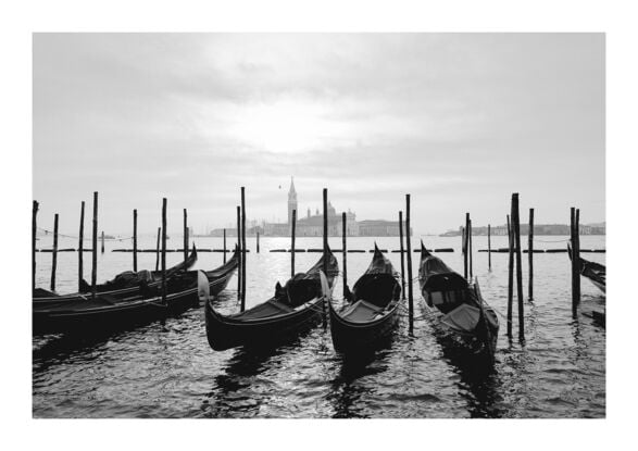 Gondolas docked at the Grand Canal in Venice with a view of a Church in the distance