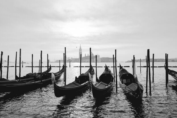 Gondolas docked at the Grand Canal in Venice with a view of a Church in the distance