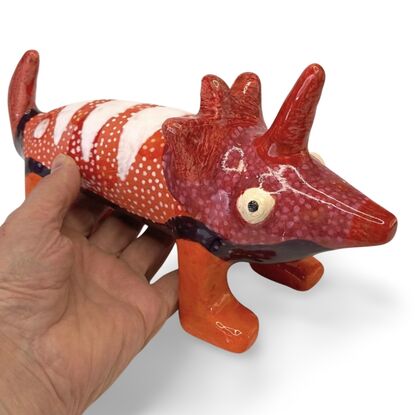 The Spotted Wombat features a playful, abstract rendition of a wombat, glazed in a striking deep blue with contrasting white circular spots and a red snout.