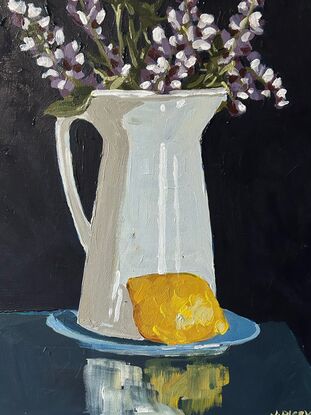 A white rustic jug serves as a vase for purple lupin flowers . it sits on a blue saucer and a lemon is in the foreground. The background is a deep blue