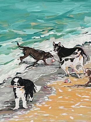 A group of five dogs romping on the beach and playing in the waves.