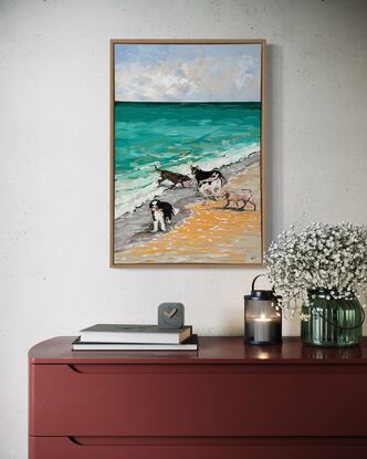 A group of five dogs romping on the beach and playing in the waves.