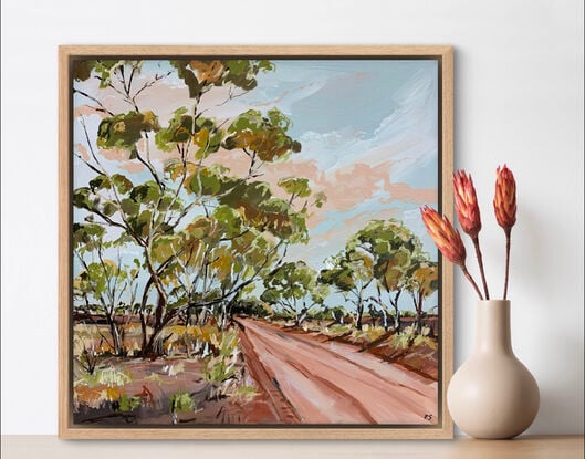 A red track is bordered by swaying gumtrees that make an archway. The blue sky is dotted with peachy clouds.