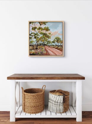 A red track is bordered by swaying gumtrees that make an archway. The blue sky is dotted with peachy clouds.