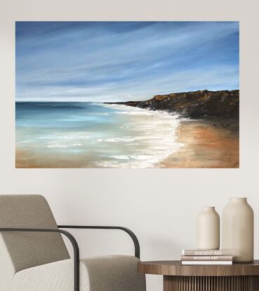 Under a blue sky with wispy white clouds sits a beachscape with a rock formation to one side that juts into a clear blue ocean with whitewash on the shoreline. 