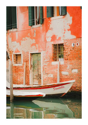 Interesting boat docked along a Venetian Canal with textured brick walls behind