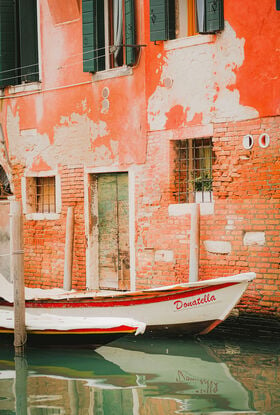 Interesting boat docked along a Venetian Canal with textured brick walls behind