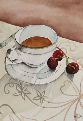 Cup and saucer on a tablecloth with cherrys