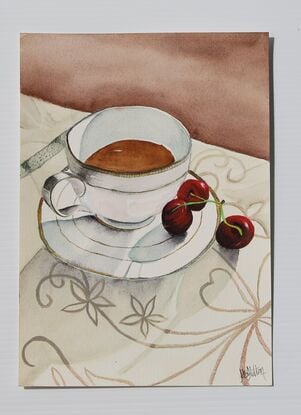 Cup and saucer on a tablecloth with cherrys