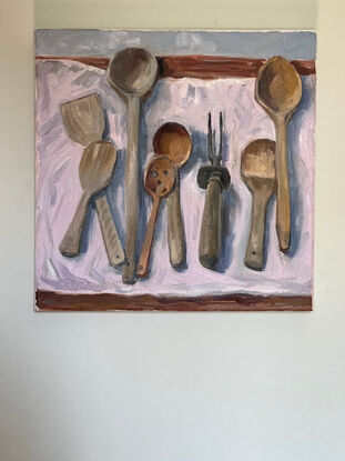 The painting depicts a collection of wooden kitchen spoons on a cloth with a kitchen carving fork.
I can be read as a metaphor for the odd one out or danger.