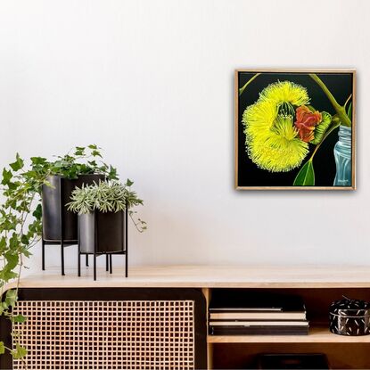 The painting features a bright yellow flower in full bloom with a red gum nut  set against a dark background. The flower rests in a simple glass jar, creating a striking contrast with the moody backdrop.