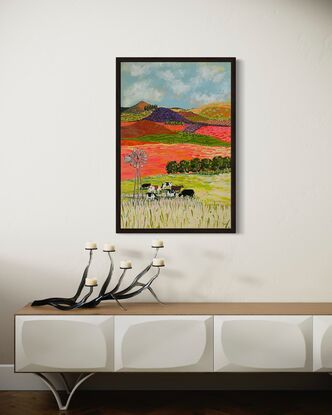 A group of cows grazing under a windmill in a bright landscape.