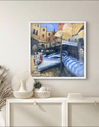 Fishing boats draped in striped canopies below a restaurant on the Italian Riviera.