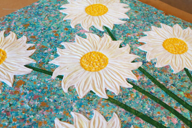 white and yellow textured flowers in a pink vase on a sky blue background