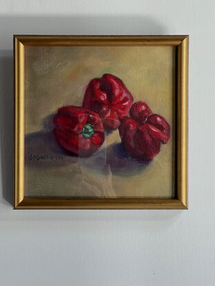 Three red capsicums on a yellow ochre background.