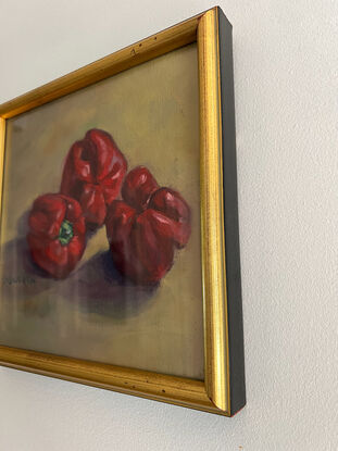 Three red capsicums on a yellow ochre background.