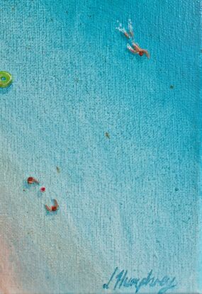 Large rocks create a lagoon swimming pool. People sunbath and swim in the water.