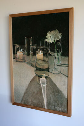 The painting depicts simple lit candles in glassware and the play of light through a surrounding range of glassware and on a single rose.