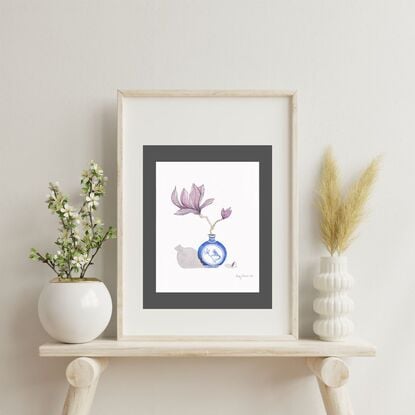 A watercolour painting of a small Chinese-style vase with a painted bird design, holding a single magnolia blossom with soft, unfolding petals. The composition is simple and serene, combining traditional elegance with natural beauty.