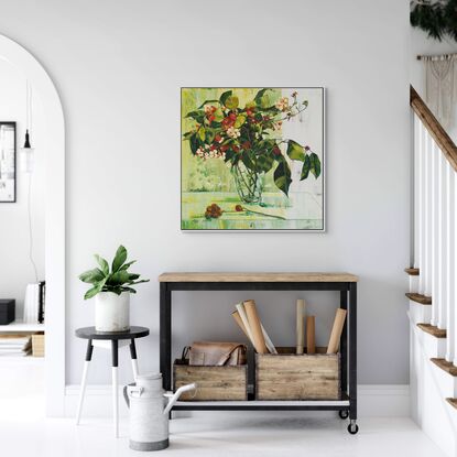 A framed limited edition canvas print in a white wood floating frame of an original still life painting of flowers in yellows, greens , reds and oranges in a glass vase