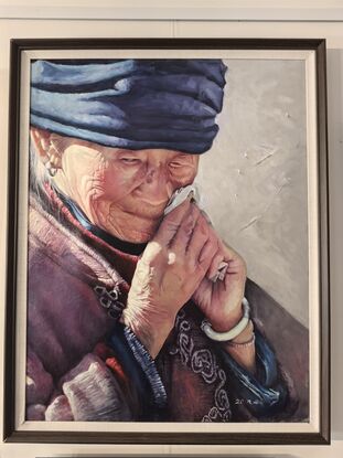 A detailed portrait of an elderly woman, wiping away a tear with a handkerchief. Her face shows deep wrinkles, and she wears a blue headscarf along with traditional clothing. Her expression is tender and introspective, with soft light emphasizing the texture of her skin and hands. The simple background keeps the focus on the woman’s face and her emotional gesture.