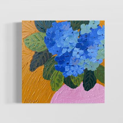 3 purple-blue hydrangeas in a light pink vase on a warm orange background. 