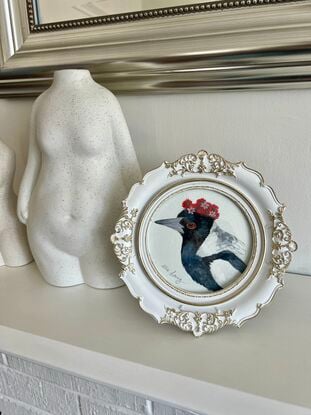 Magpie with a flower crown in an ornate white and gold frame. 