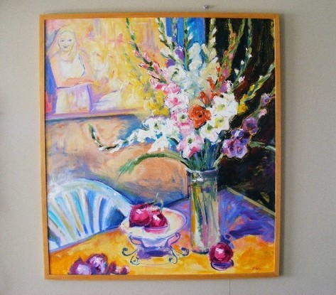 Various colored Gladioli in a clear vase , red onions in a clear glass bowl, and a painting is hanging on the wall