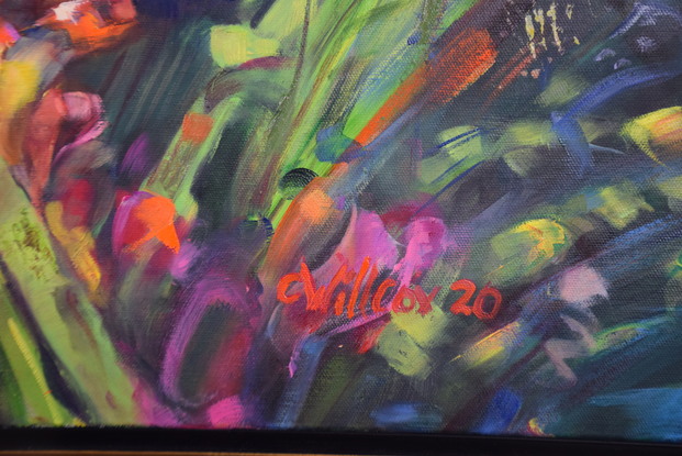 This a close up of yellow, red and orange freesia growing,  with a dark background.  The painting has a gold floating frame.