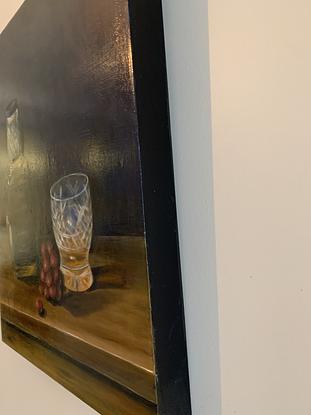 Whiskey bottle and crystal glass sitting on a wooden table with some grapes.