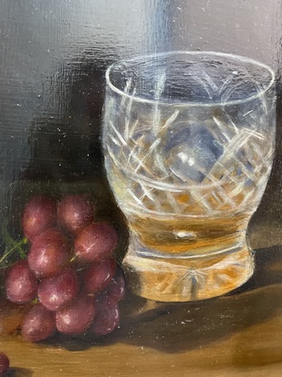 Whiskey bottle and crystal glass sitting on a wooden table with some grapes.