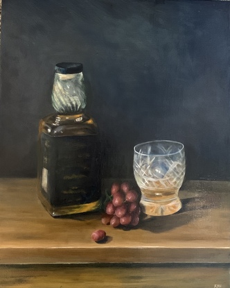 Whiskey bottle and crystal glass sitting on a wooden table with some grapes.