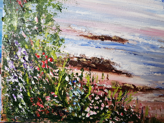 Evening at Sunset Beach in Port Stephens. A yellow and red boat on the sand. Greenery and wild flowers in the foreground. Lots of sailing boats on the water. Point Restaurant and The Boat Shed in the distance. The sky is dark blue and pink. The sand is pinkish.  